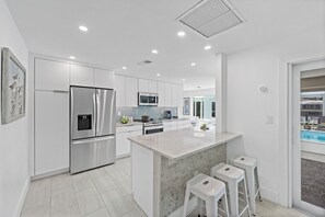 A modern kitchen with stainless steel appliances, a central island, and a view of an outdoor pool.