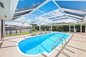 A covered outdoor swimming pool with lounge chairs and a view of the water. - Direct Boating Access | Olde Marco Home w/ Pool (Marco Island)