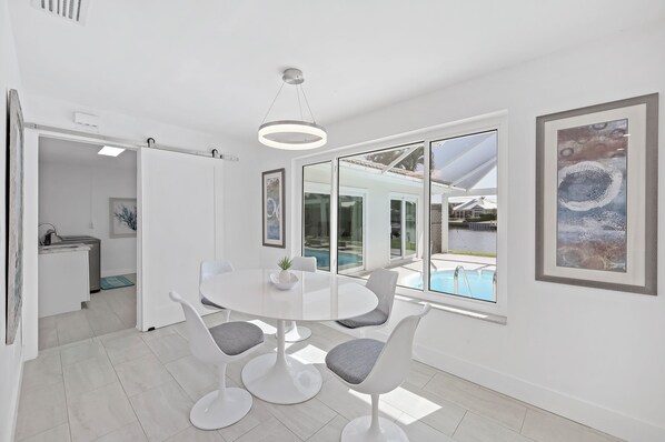 Enjoy meals around a large dining table with four chairs in a room with a pool view.