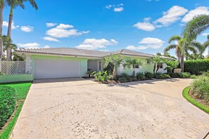 A two-story house with a tiled roof, a garage, and a well-maintained lawn.