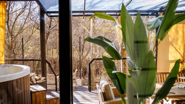 A wooden deck with a hot tub, wicker furniture, and a view of leafless trees. - Gipsy Village (Tetritskaro)