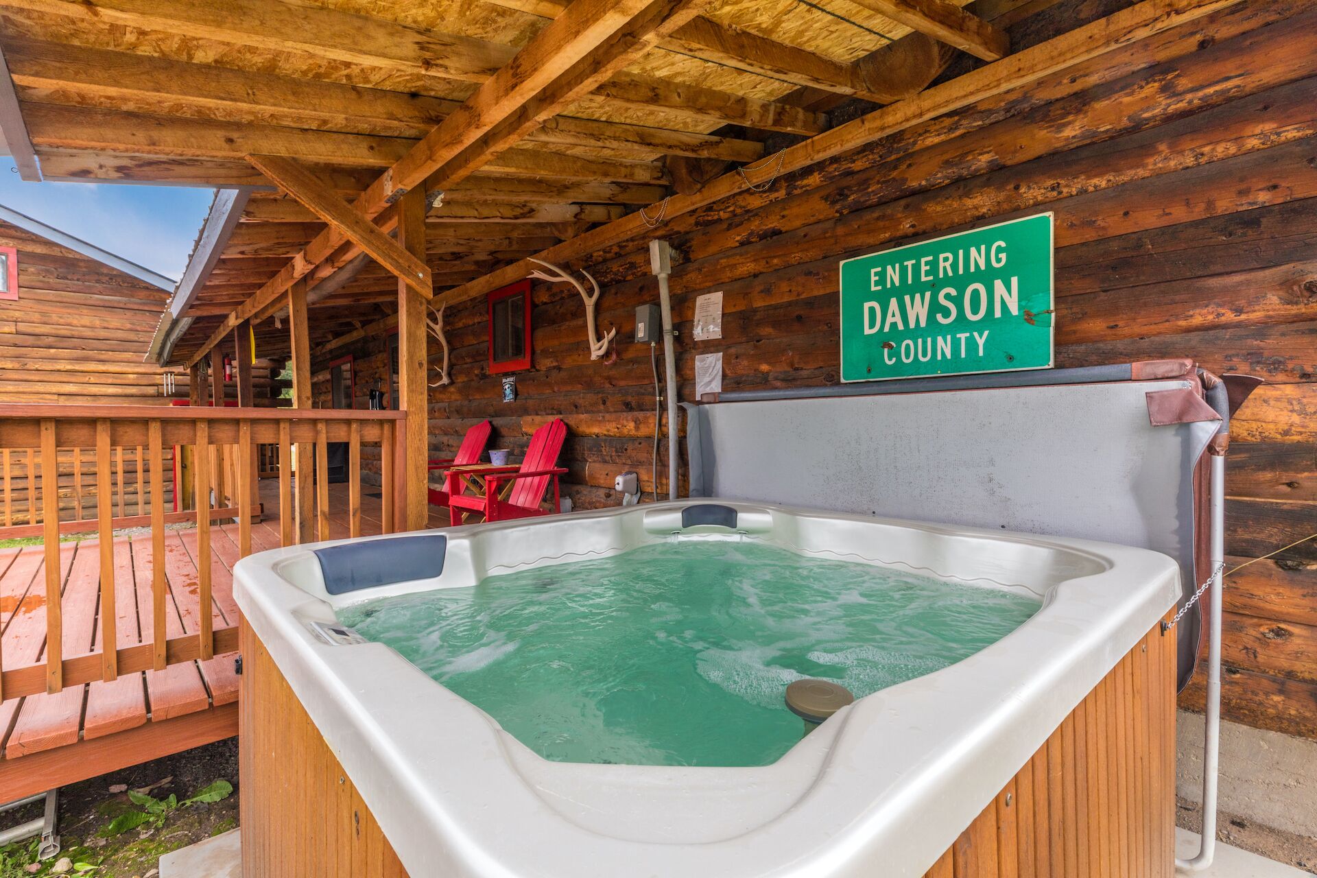 A wooden cabin with a hot tub and a sign indicating entry into Dawson County.