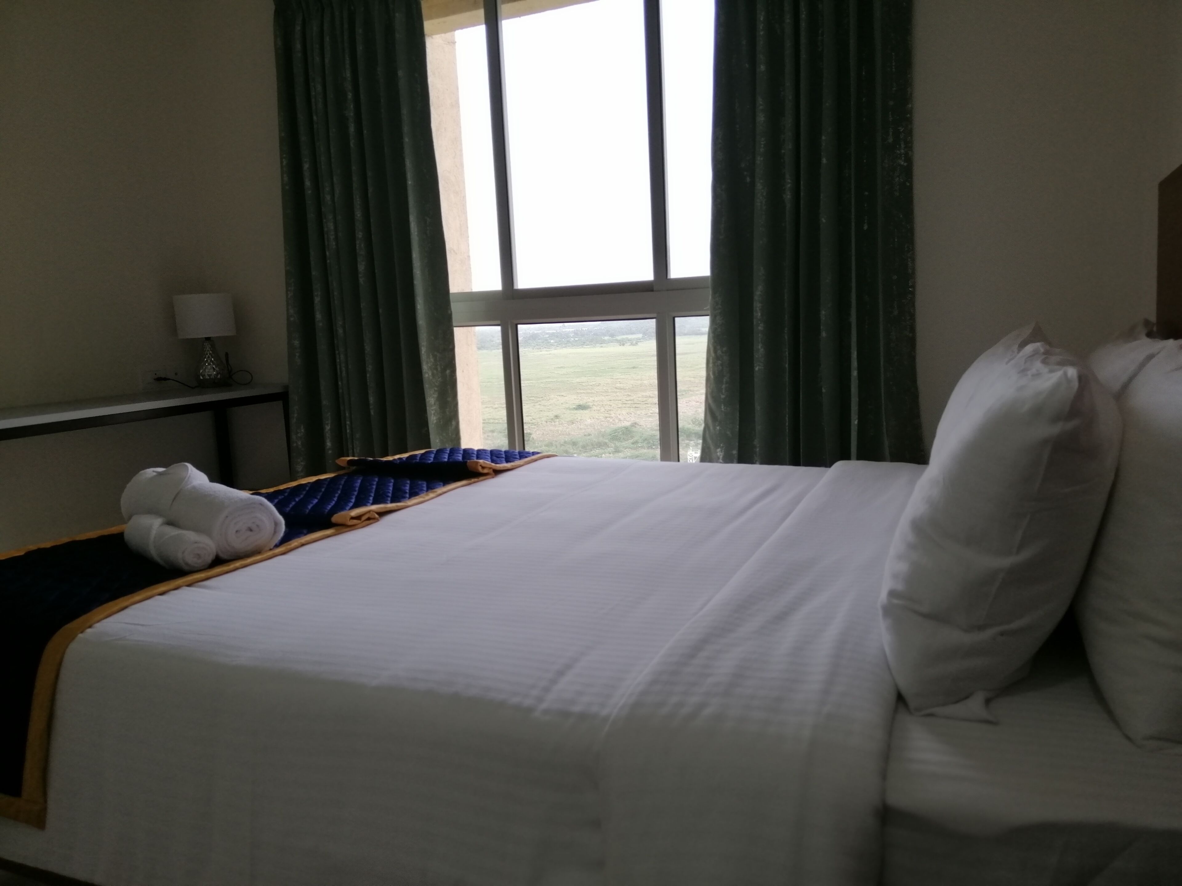 Habitación de hotel con una cama, una mesita de noche y vistas al exterior.