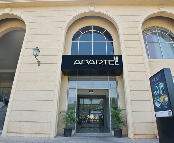 Un immeuble avec une enseigne indiquant « APARTEL » au-dessus de l’entrée.