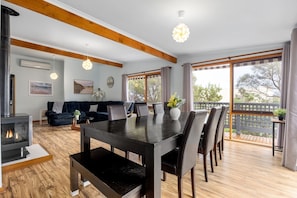 A modern living room with a fireplace, a dining table, and a sofa. - Charming Rye Beach Retreat (Rye)