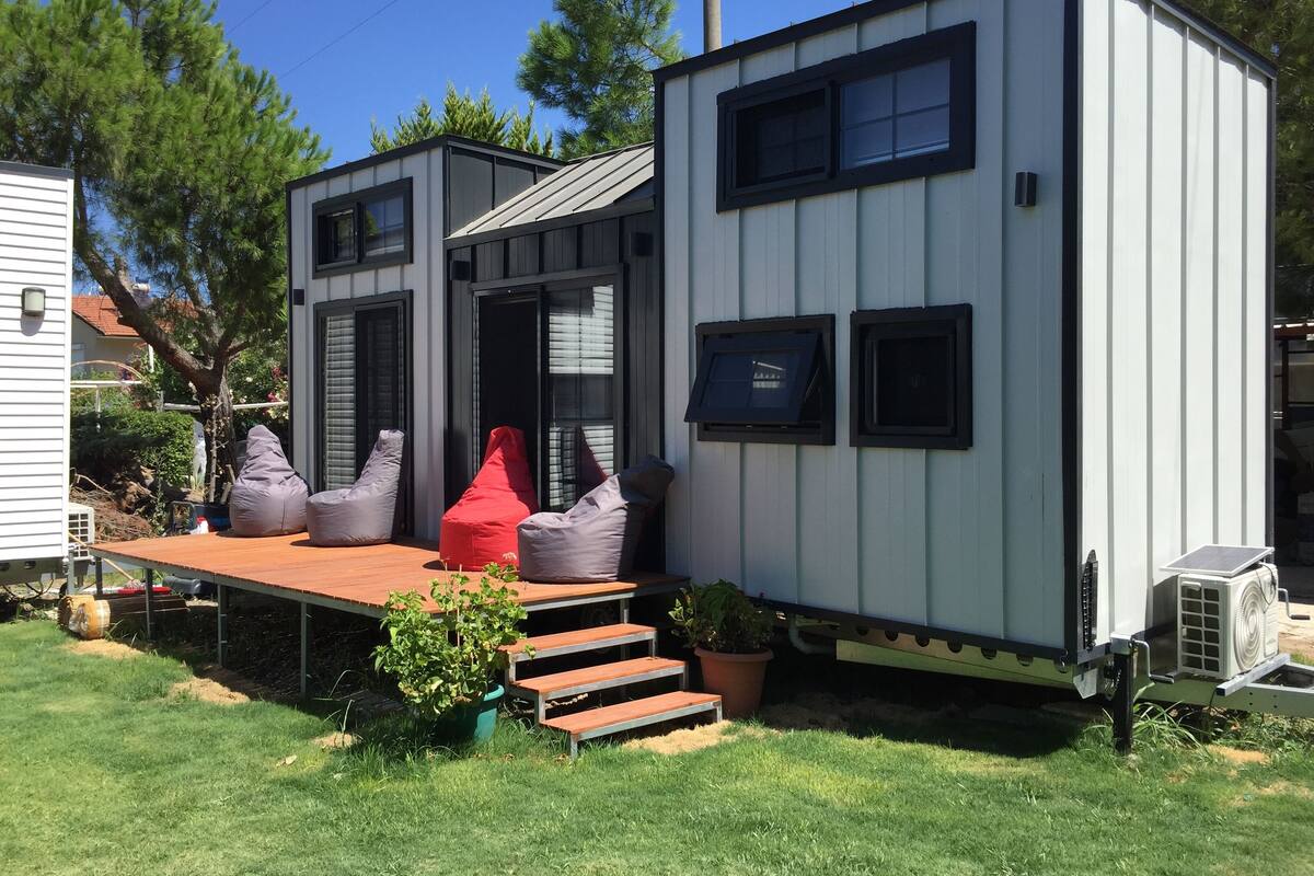 A modular home with a deck, outdoor seating, and a small garden area.