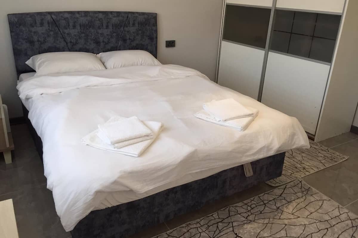 A modern bedroom with a large bed, white linens, and neatly folded towels.