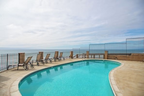 Relax by the ocean-view pool surrounded by lounge chairs and a secure boundary.