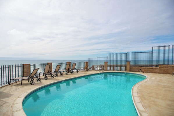 A swimming pool with lounge chairs and a view of the ocean. - 10% OFF last minute stays - Oceanfront 1 bedroom, Pool, Spa, Beach Access (Solana Beach)