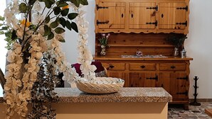 A kitchen with wooden cabinets, a granite countertop, and a vase with white flowers. - *merlin apartment near the Giaveno Sanctuary, 5 km from the Avigliana lakes (Giaveno)