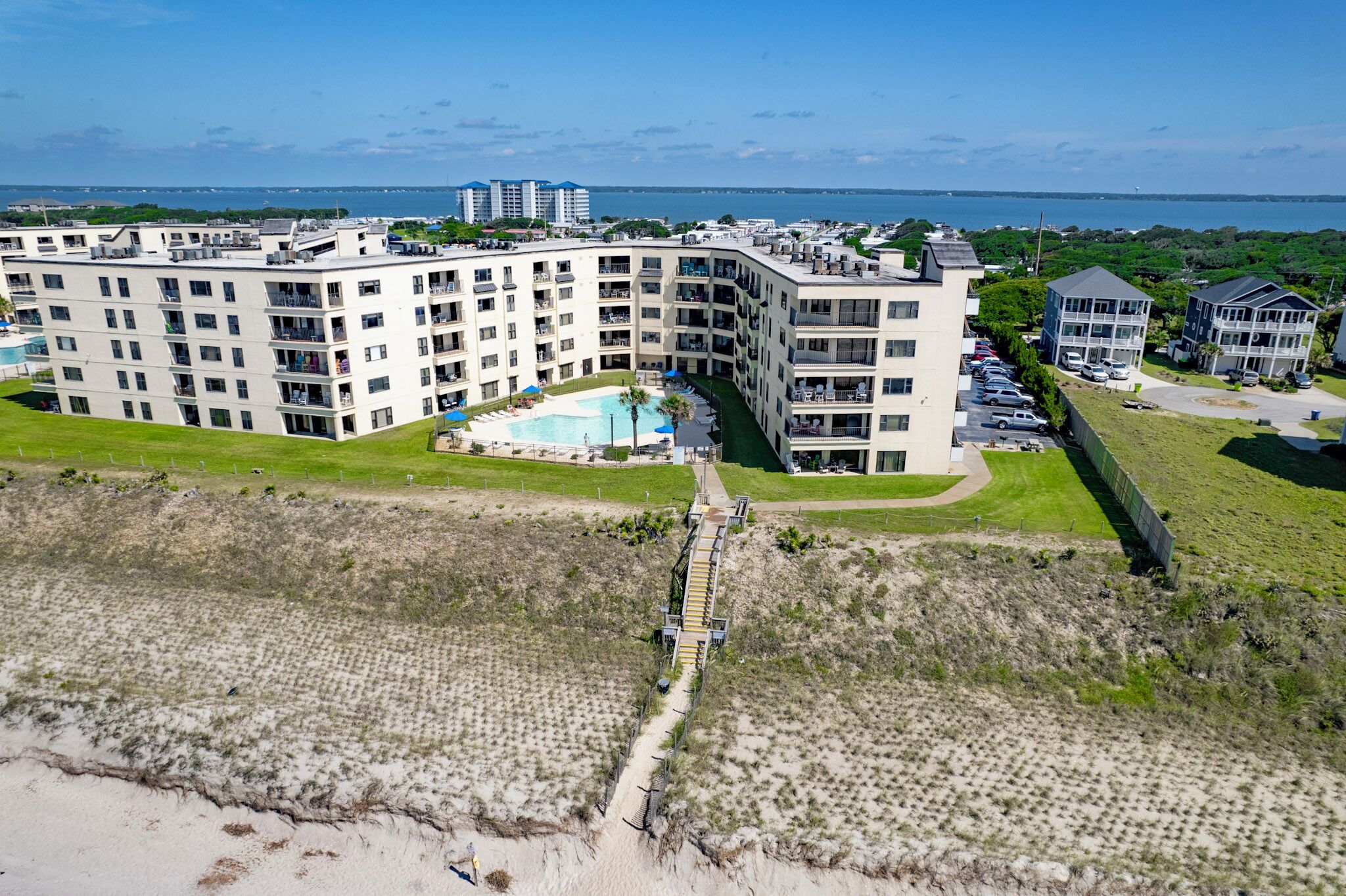 A multi-story hotel with a swimming pool, located near a beach.