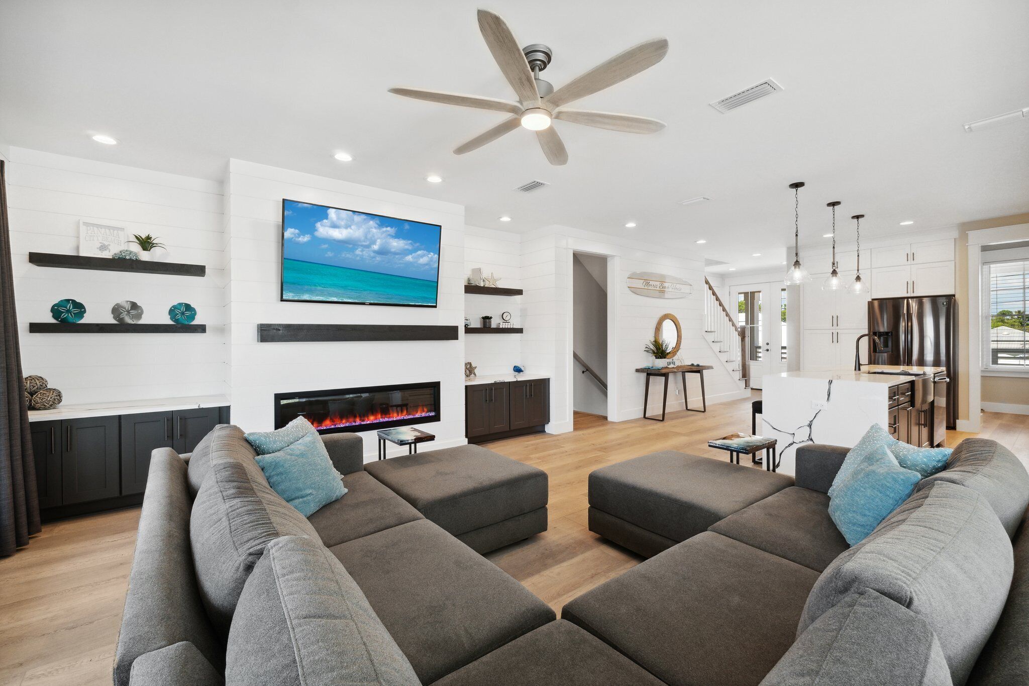 A modern living room with a fireplace, grey sofas, and a TV mounted on the wall.