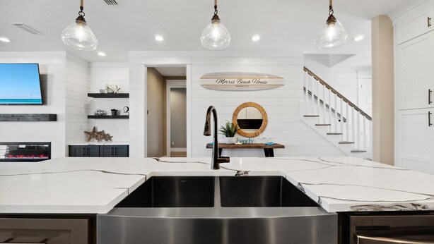 A modern kitchen with a large island, stainless steel appliances, and pendant lighting.