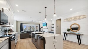 A modern kitchen with a central island, built-in appliances, and pendant lighting.