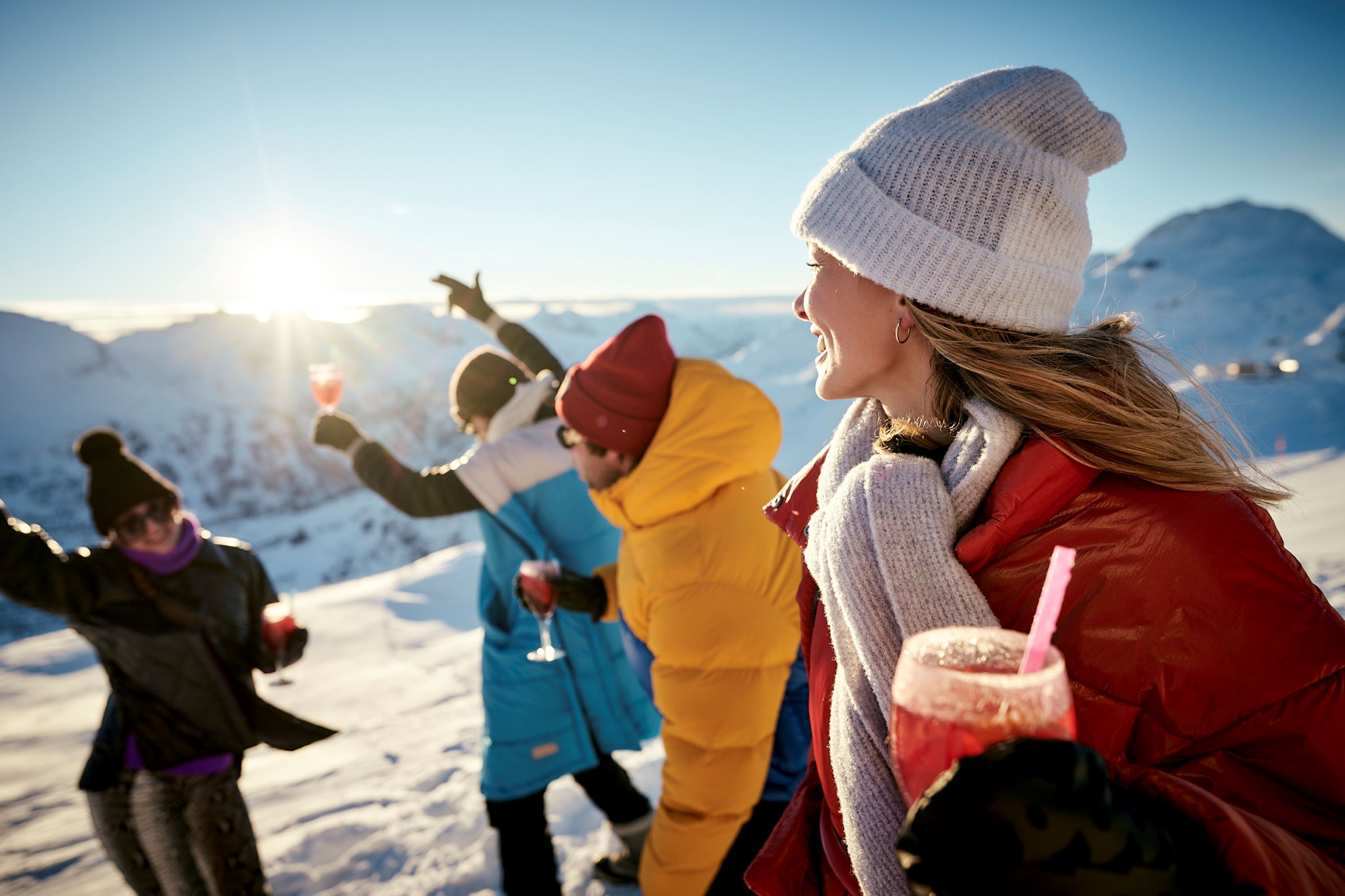 A group of people enjoying a snowy outdoor setting with mountains in the background.