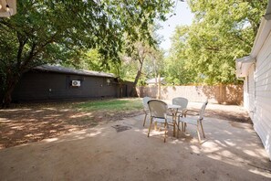 Un jardin avec un espace patio, un petit bâtiment et une clôture en bois.