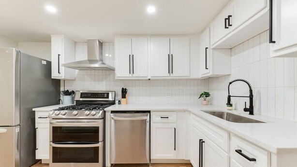 A modern kitchen with white cabinets, stainless steel appliances, and a black faucet. - Chateau Urbane- a luxe escape (Norman)