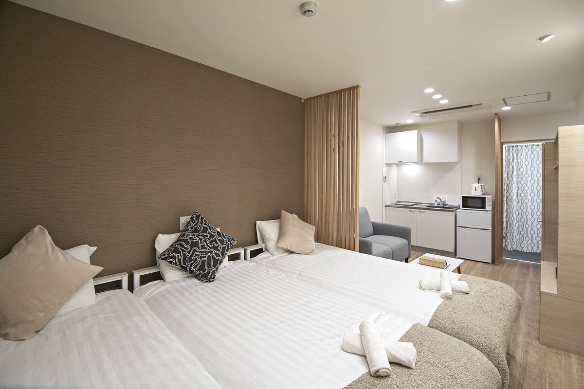 A hotel room with a large bed, a desk, and a kitchenette.