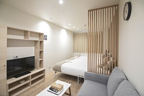 A modern hotel room with a flat-screen TV, a sofa, a bed with a wooden headboard, and a sliding wooden partition. - shiye house (Osaka)
