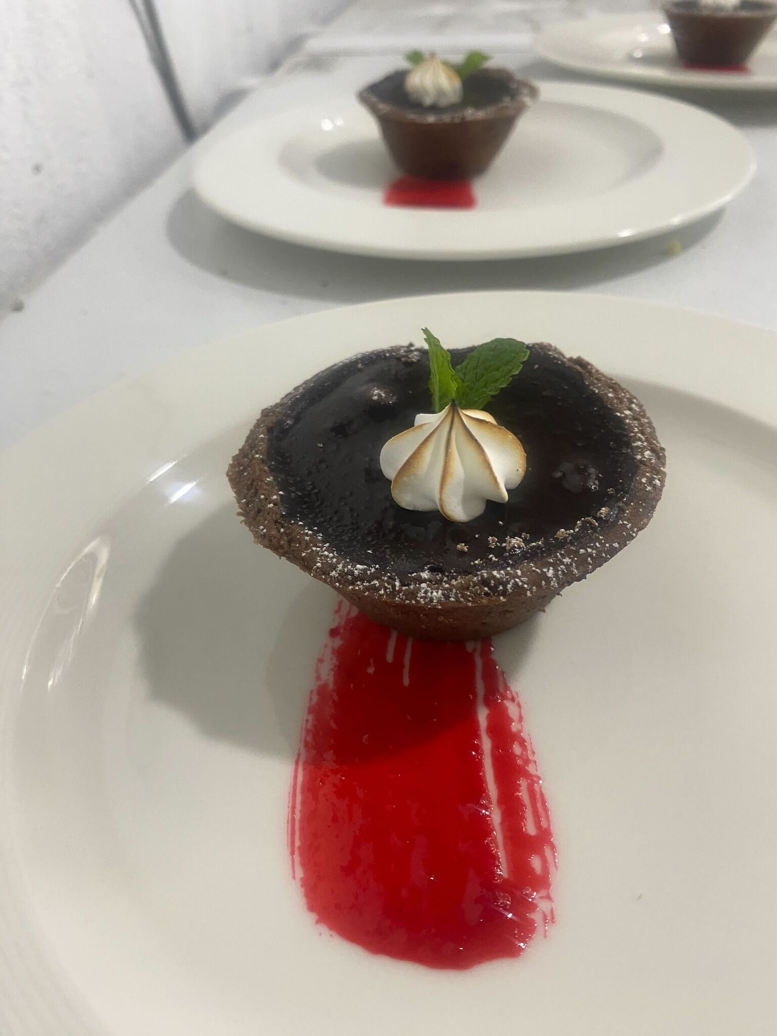 A dessert on a white plate with a red sauce.