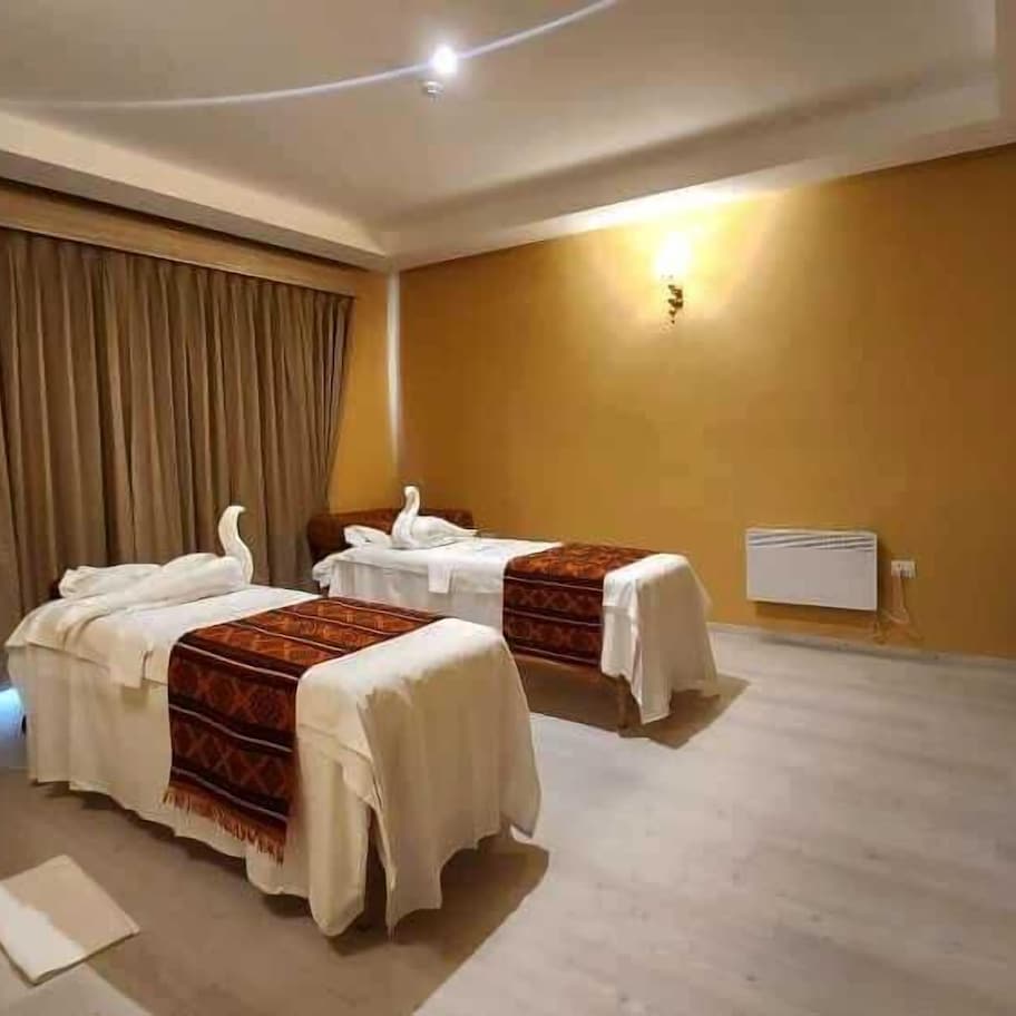 A hotel room with two beds, a sofa, a desk, and a bathroom.