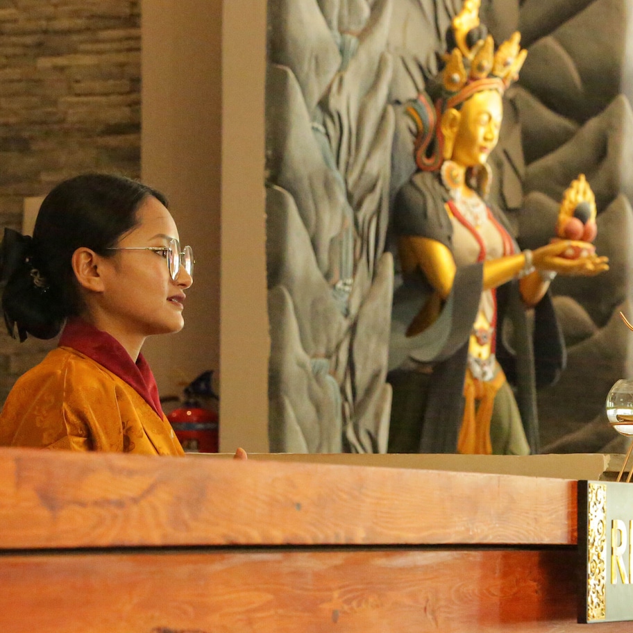 A reception desk with a sign labeled "RECEPTION" and a statue in the background.