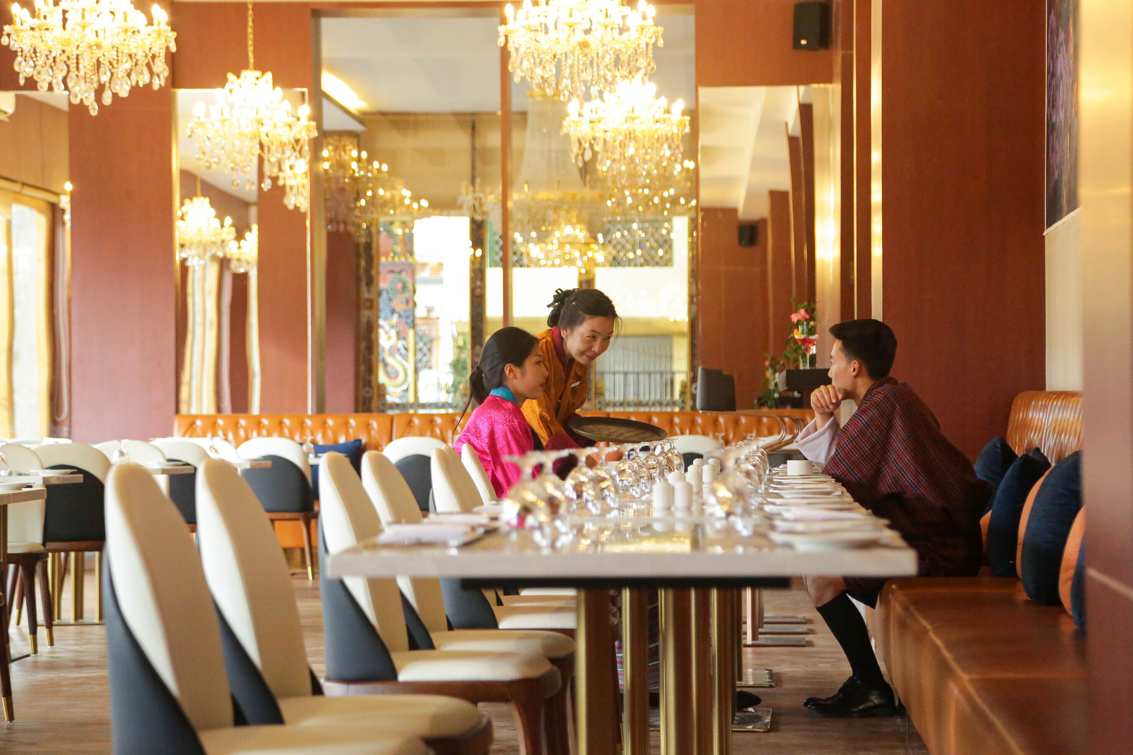 A restaurant with a long dining table set for a meal, surrounded by chairs.