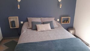 A neatly arranged bedroom with a bed, pillows, a bedside table, and wall-mounted lights. - House between sea, pool and garrigue (Cuxac-d'Aude)