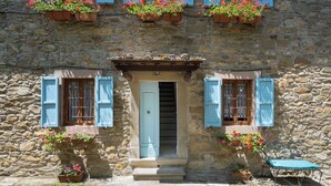 A stone building with a central door, blue shutters, and flower boxes. - Podere La Vigna (Borgo San Lorenzo)