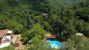 A mountainous landscape with a swimming pool surrounded by trees and a small house. - Podere La Vigna (Borgo San Lorenzo)