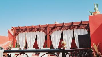 A red-roofed building with white curtains and a decorative metal railing.