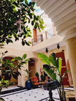 Un patio con una fuente, plantas en macetas y asientos al aire libre.