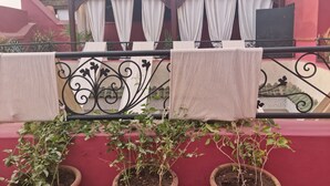 A balcony with potted plants, white curtains, and a metal railing. - Riad La Bigarade (Marrakech)