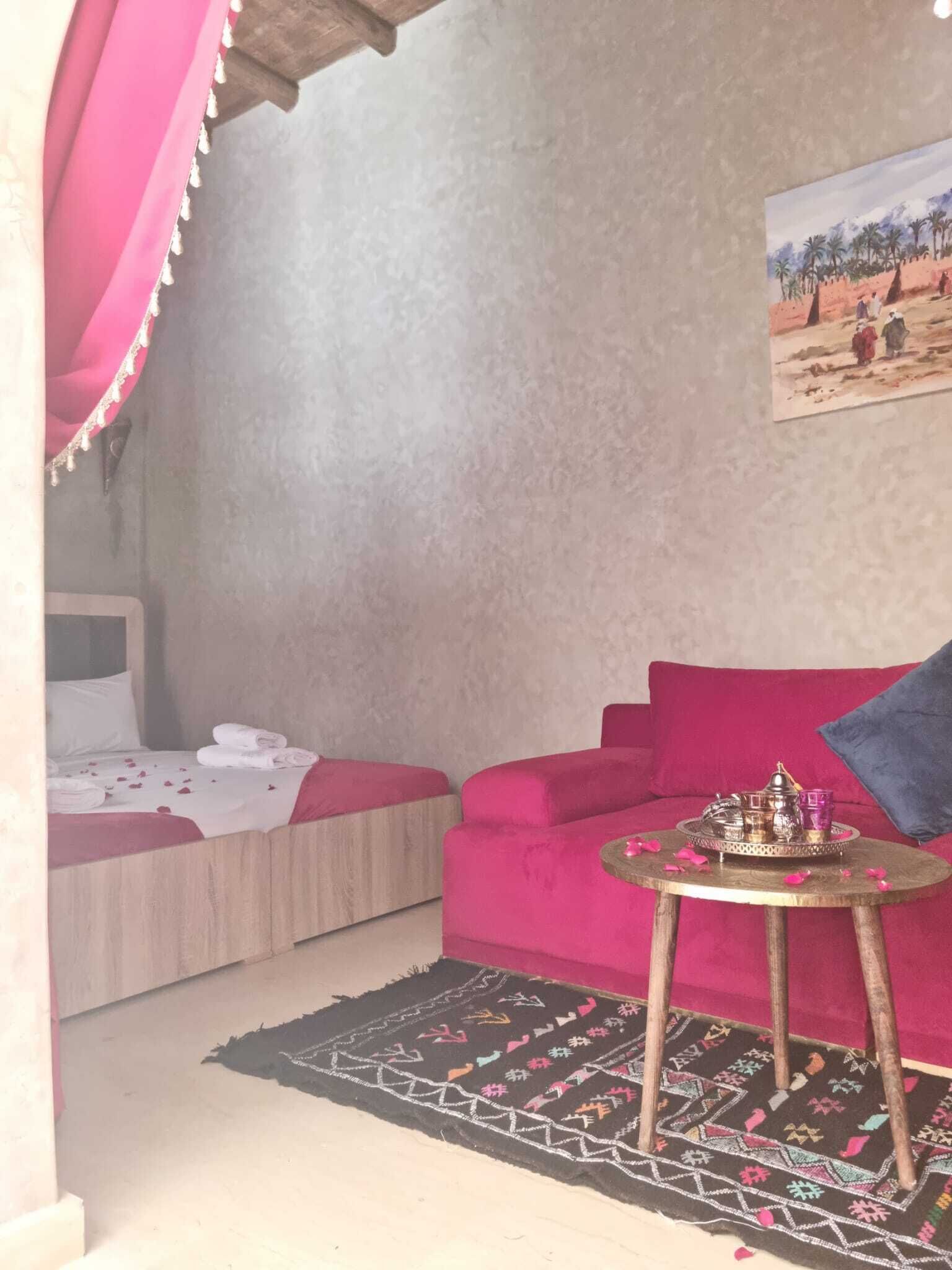Una habitación con cama, sofá, una mesita con bandeja y una alfombra estampada.