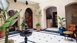 A spacious courtyard with a fountain, potted plants, and traditional seating. - Riad La Bigarade (Marrakech)