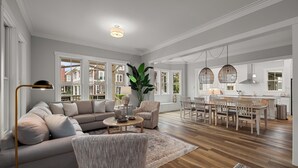 A spacious living area with a sofa, armchairs, a dining table, and a kitchen in the background. - Seabrook Main House Plus Guest House | Hot Tub Spa | 16+ Guests, Dog Friendly, T (Pacific Beach)