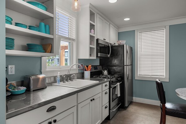 A modern kitchen with white cabinets, a black refrigerator, and a stainless steel stove. - Seabrook Main House Plus Guest House | Hot Tub Spa | 16+ Guests, Dog Friendly, T (Pacific Beach)