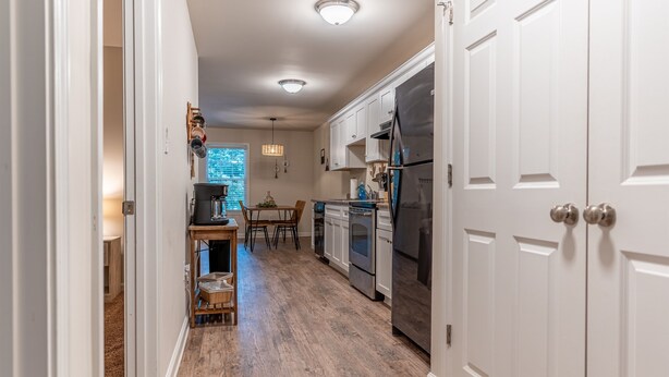 A kitchen with white cabinets, a stainless steel refrigerator, and a dining area with a table and chairs. - Near Atrium & town, King/Queen/Pullout, NO stairs (Lincolnton)