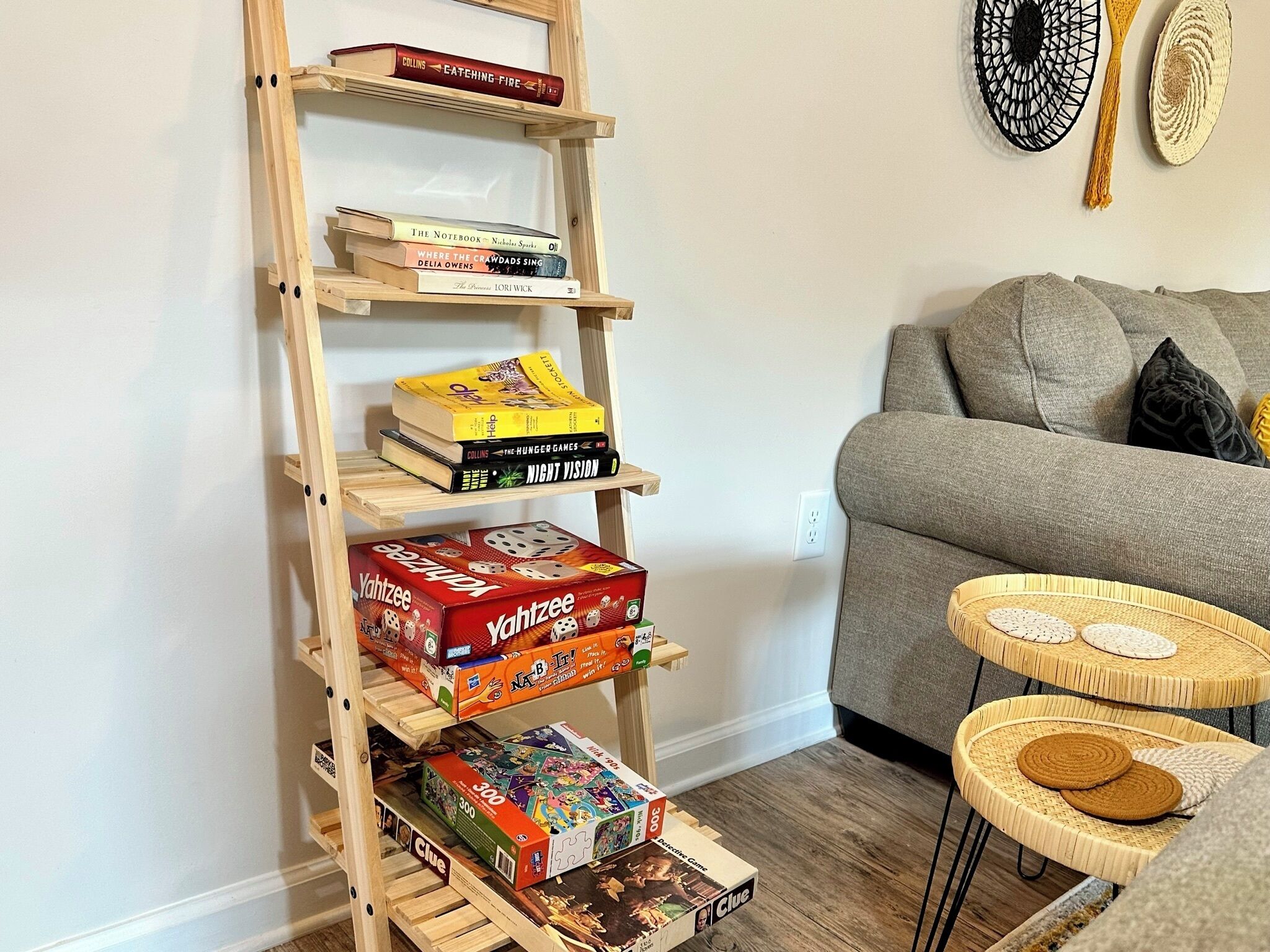 A wooden ladder shelf with books and board games.