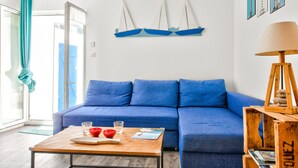 A modern living room with a blue sofa, a wooden coffee table with red bowls and glasses, and a wooden lamp. - Near the port of Guilvinec, town house for 5 (Le Guilvinec)