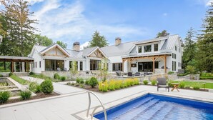 Une maison moderne dotée d’une piscine, d’un espace salon extérieur et d’un jardin bien entretenu.