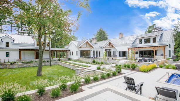 Une maison moderne dotée d’un grand jardin, d’un espace extérieur aménagé pour se détendre et d’une piscine.