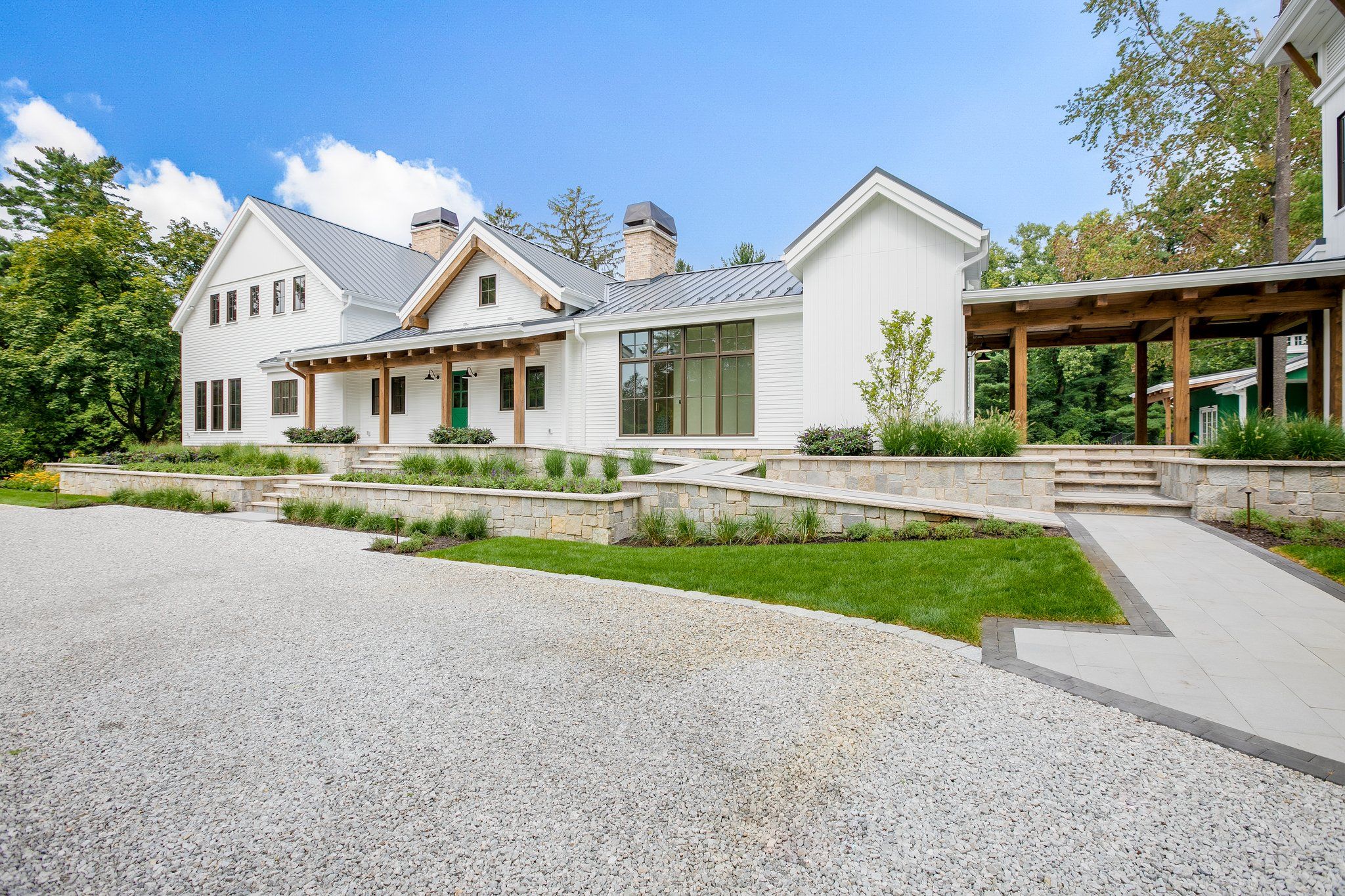 Une maison moderne à deux étages, dotée de fondations en pierre, d’un porche couvert et d’une pelouse bien entretenue.