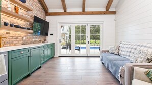 A kitchen with green cabinets, a brick wall, and a TV mounted above the counter.