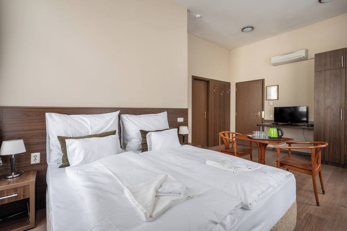 Une chambre d’hôtel avec un grand lit, un bureau avec une chaise, une télévision et une kitchenette.