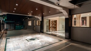 A spacious lobby with a marble floor, glass partitions, and a modern ceiling design. - Treebo Kaveri (Nashik)