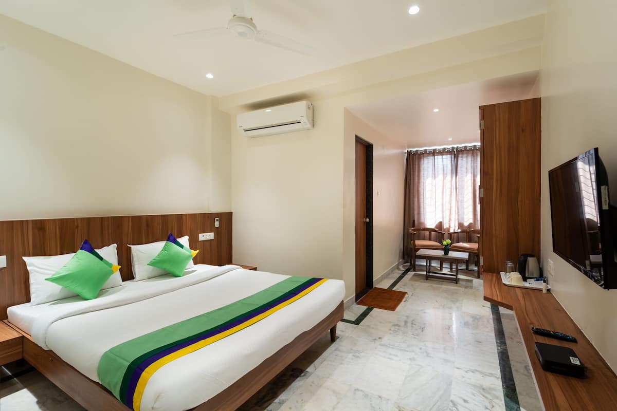 A hotel room with a large bed, a desk, a TV, and a bathroom visible through an open door.