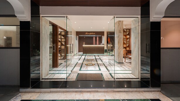 A reception area with a marble floor, a reception desk, and a reception sign. - Treebo Kaveri (Nashik)