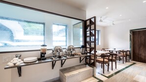 A modern bathroom with a large mirror, a countertop with various toiletries, and a seating area with chairs and a table. - Treebo Kaveri (Nashik)