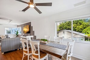 Ein stilvoller Essbereich mit Holztisch, weißen Stühlen und Deckenventilator.